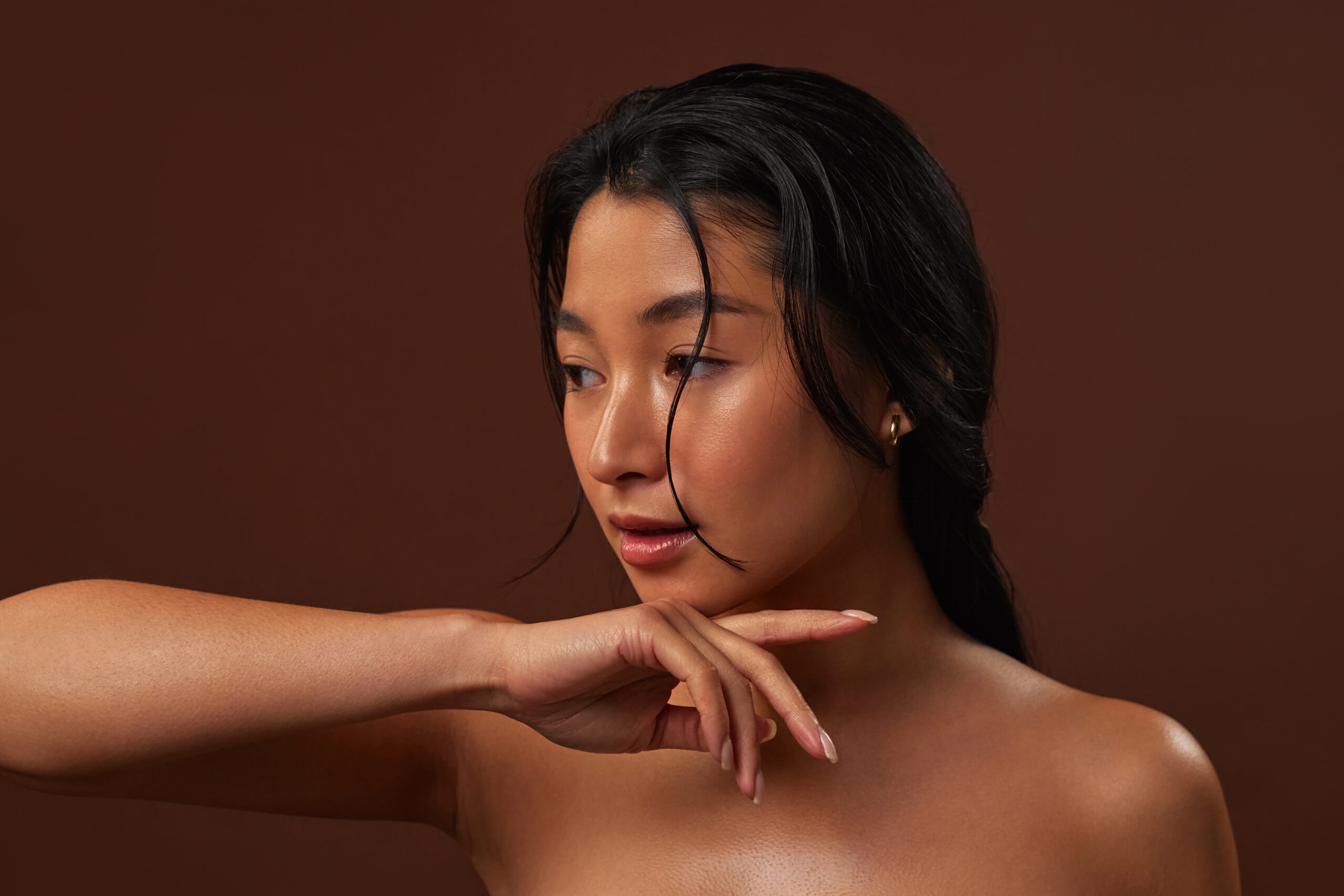 Asian woman with radiant smooth clean skin isolated on dark background. Cosmetology concept and skin care of the face and body, spa treatments.